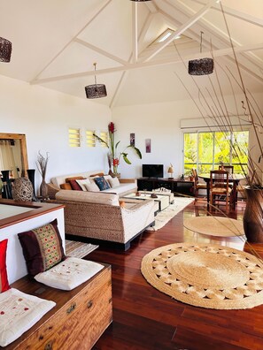 A spacious living room with a high ceiling, a large window, and a dining area. - Villa Samaé, Tropical charm in the south-west of Reunion Island (Les Avirons)