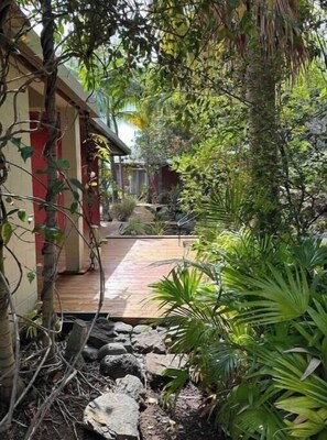 A garden pathway leading to a building with a red and white facade, surrounded by lush greenery and rocks. - Villa Samaé, Tropical charm in the south-west of Reunion Island (Les Avirons)