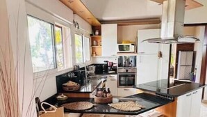 Een moderne keuken met een centraal eiland, geïntegreerde apparatuur en veel daglicht.