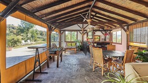 A covered outdoor area with a foosball table, dining table, and chairs.
