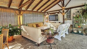 A covered outdoor seating area with a sofa, chairs, and a table.