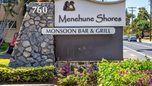 A sign for Menuhe Shores Monsoon Bar & Grill, featuring a stone pillar with the number 760 and a logo of two people. - Amazing Oceanfront Views! MS420 (Kihei)