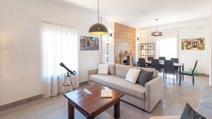 A modern living room with a sofa, coffee table, and dining area. - Villa Los Ruedos Riogordo by Ruralidays (Málaga)