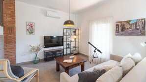 A modern living room with a TV, bookshelf, and a telescope. - Villa Los Ruedos Riogordo by Ruralidays (Málaga)
