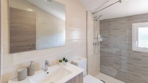 A modern bathroom with a large mirror, a sink, a toilet, and a glass-enclosed shower area. - Villa Los Ruedos Riogordo by Ruralidays (Málaga)