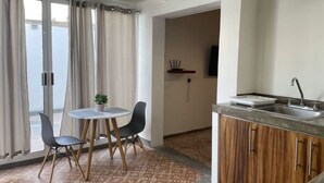 Una cocina moderna con armarios de madera, una mesa redonda con dos sillas y vistas a través de la puerta de cristal.