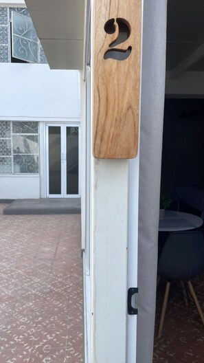 A wooden door with a number '2' sign, a white door frame, and a glass door with a metal gate. - La paz Apartments (La Paz)