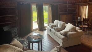 A cozy log cabin interior with a sofa, a small table, and a fireplace. - Beaverfoot Lodge (Golden)