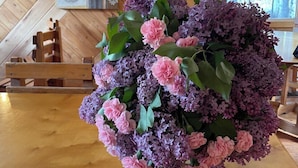 A wooden table with a floral arrangement in a room with wooden walls and a window. - Beaverfoot Lodge (Golden)