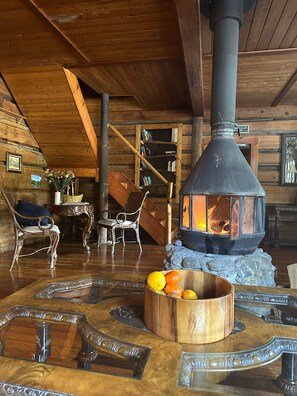 Un interior de cabaña acogedor con un estufa de leña, muebles rústicos y una chimenea de piedra.
