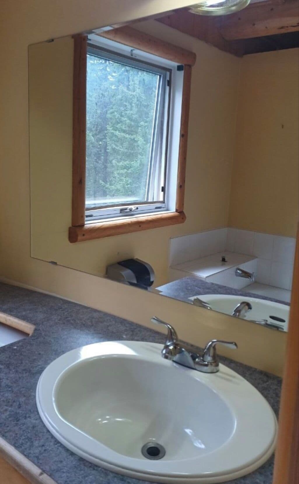 A bathroom with a large sink, a mirror, and a window.