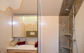 Bathroom features a large mirror, sink, and shower with handheld showerhead.