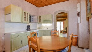 A kitchen with a wooden table and chairs, light green cabinets, and a coffee maker. - 2 bedroom gorgeous apartment in Poggio Di Nazza (Poggio Di Nazza)