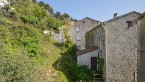 A narrow street with stone buildings, some with visible windows and doors, surrounded by greenery and trees. - 2 bedroom gorgeous apartment in Poggio Di Nazza (Poggio Di Nazza)