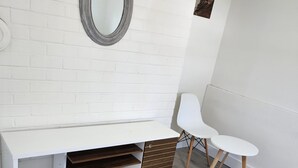 Eine weiße Ziegelwand mit einem weißen Waschtisch, einem runden Spiegel und einem kleinen Tisch.