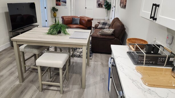 Ein modernes Wohnzimmer mit Fernseher, Sofa und Essbereich.