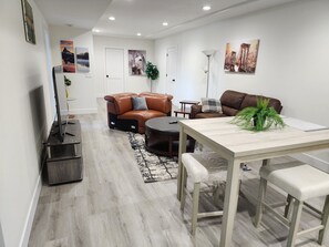 A modern living room with a sofa, a dining table, and a TV.