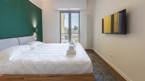 A hotel room with a bed, a large window, a radiator, and a mounted television. - Guido Monaco in Florence by Mmega (Firenze)