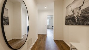 A hallway with a wooden floor, a large mirror, and a painting of a cow. - Guido Monaco in Florence by Mmega (Firenze)