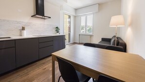 A modern kitchen with dark cabinetry, a marble backsplash, and a large window. - Guido Monaco in Florence by Mmega (Firenze)