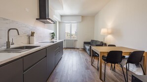 A modern kitchen with a built-in stove, a sink, and a dining area with a table and chairs. - Guido Monaco in Florence by Mmega (Firenze)