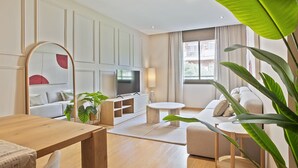 Una sala de estar moderna con una mesa de centro de madera, un sofá, un televisor y un espejo grande.