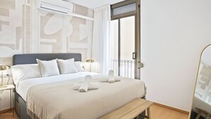 Un dormitorio moderno con una cama grande, un banco, una mesita de noche con lámpara y un equipo de aire acondicionado.