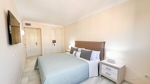 Une chambre à coucher avec un lit, des tables de chevet, un miroir et une porte.