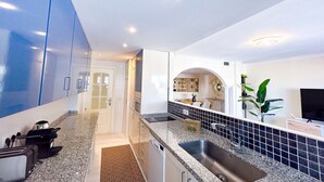 Une cuisine moderne dotée de plans de travail en granit, d’un évier en acier inoxydable et d’un pare-feu en carreaux bleus.