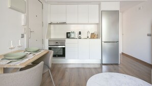 Une cuisine moderne avec des meubles blancs, un réfrig érateur en acier inoxydable et un coin repas comprenant une table et des chaises.
