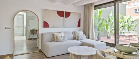A modern living room with a sofa, a round coffee table, and a dining area with a table and chairs.