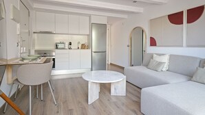 Un salon moderne avec un canapé gris, une table basse ronde et un coin repas comprenant une table et des chaises en bois.