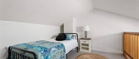 A bedroom with a bed, bedside table, lamp, and a small rug.