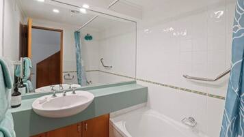 A bathroom with a sink, mirror, and shower.
