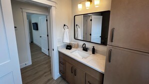 Une salle de bain moderne avec un grand miroir, deux lavabos et un meuble-lavabo avec des placards.