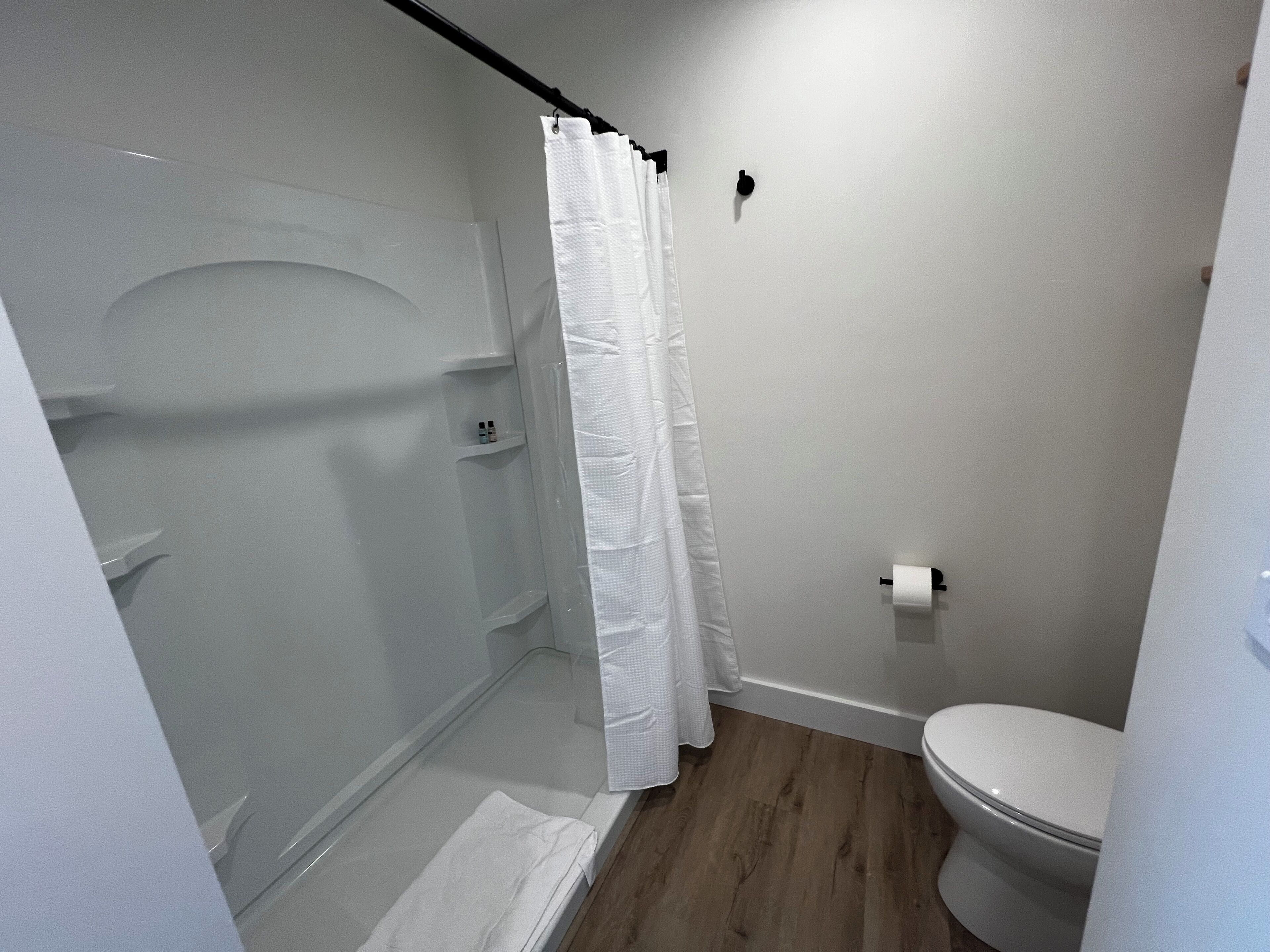 A bathroom with a shower, toilet, and a towel rack.