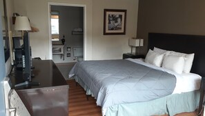 Habitación de hotel con cama, escritorio, televisor, baño y un cuadro en la pared.