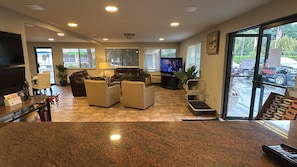 Een hotel lobby met een flatscreen televisie, leren banken, een bijzettafeltje en een receptiebalie met een plant.