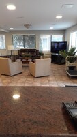 Una sala de estar con una televisión de pantalla plana, dos sofás, una mesa de centro y una planta en maceta.