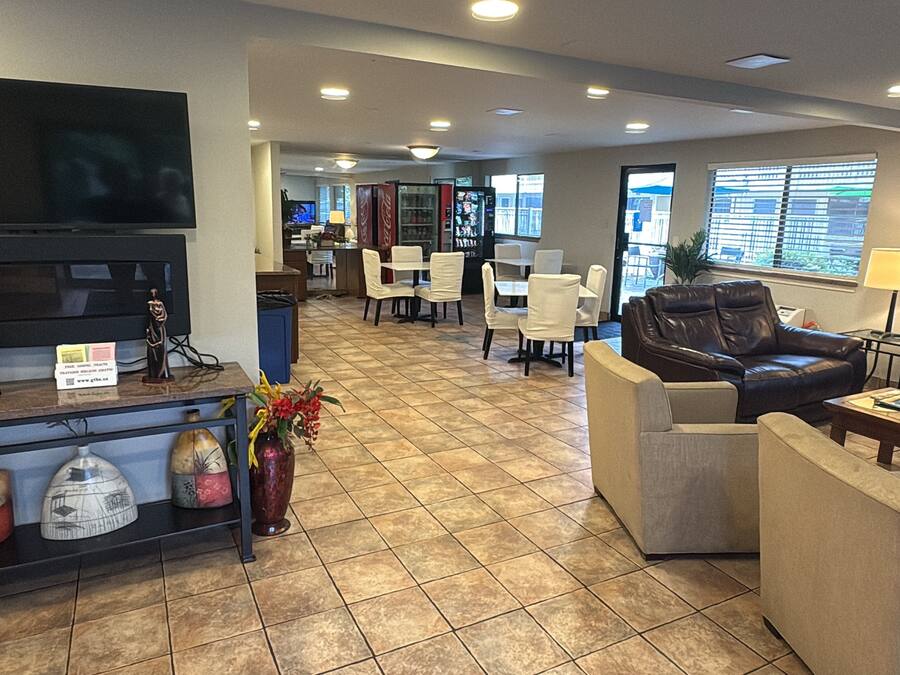 A hotel lobby with a flat-screen TV, seating area, and a Coca-Cola refrigerator.