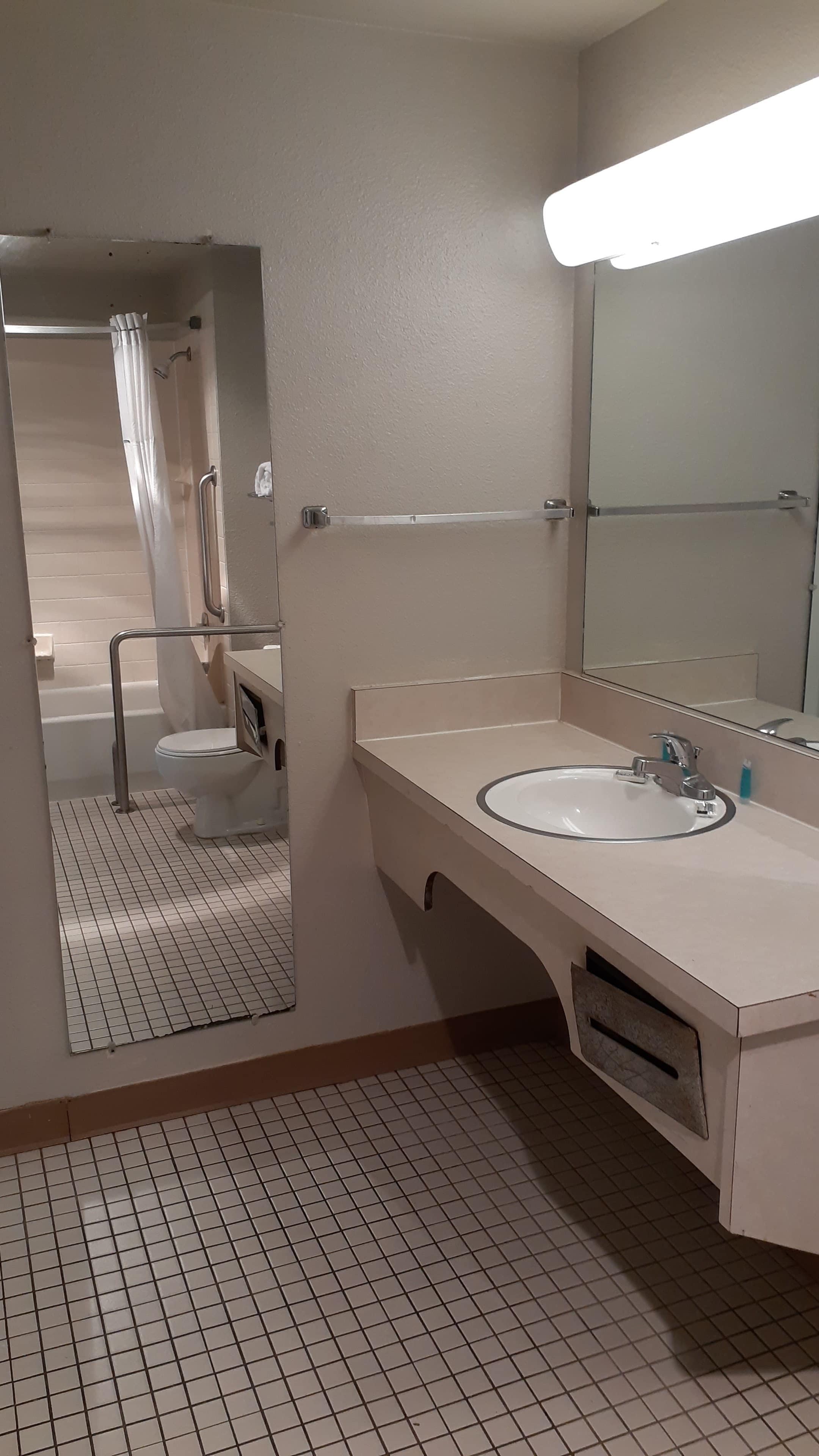 Ein Badezimmer mit einem weißen Waschbecken, einem Spiegel und einem Duschbereich mit Glastür.