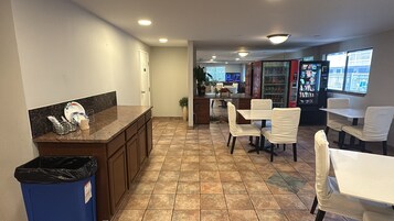 Un espacio interior limpio y bien iluminado con mostrador, zona de estar y máquinas expendedoras.