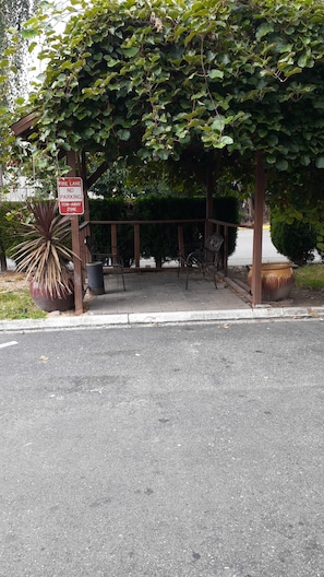 Una calle de acceso para bomberos con un letrero de 'prohibido estacionar', un banco y una jardinera con una planta grande.