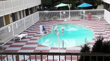 Un área de piscina con suelo a cuadros, sillas de descanso y sombrillas.