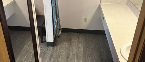 A small bathroom with a wooden floor, a toilet, a mirror, and a towel rack.