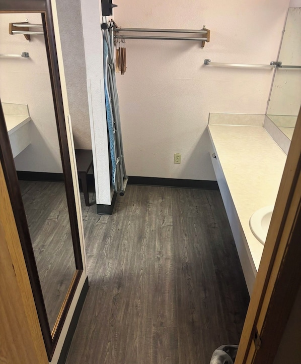 A small bathroom with a wooden floor, a toilet, a mirror, and a towel rack. - Seattle Value Inn Near Tacoma Airport I-5 (Tukwila)