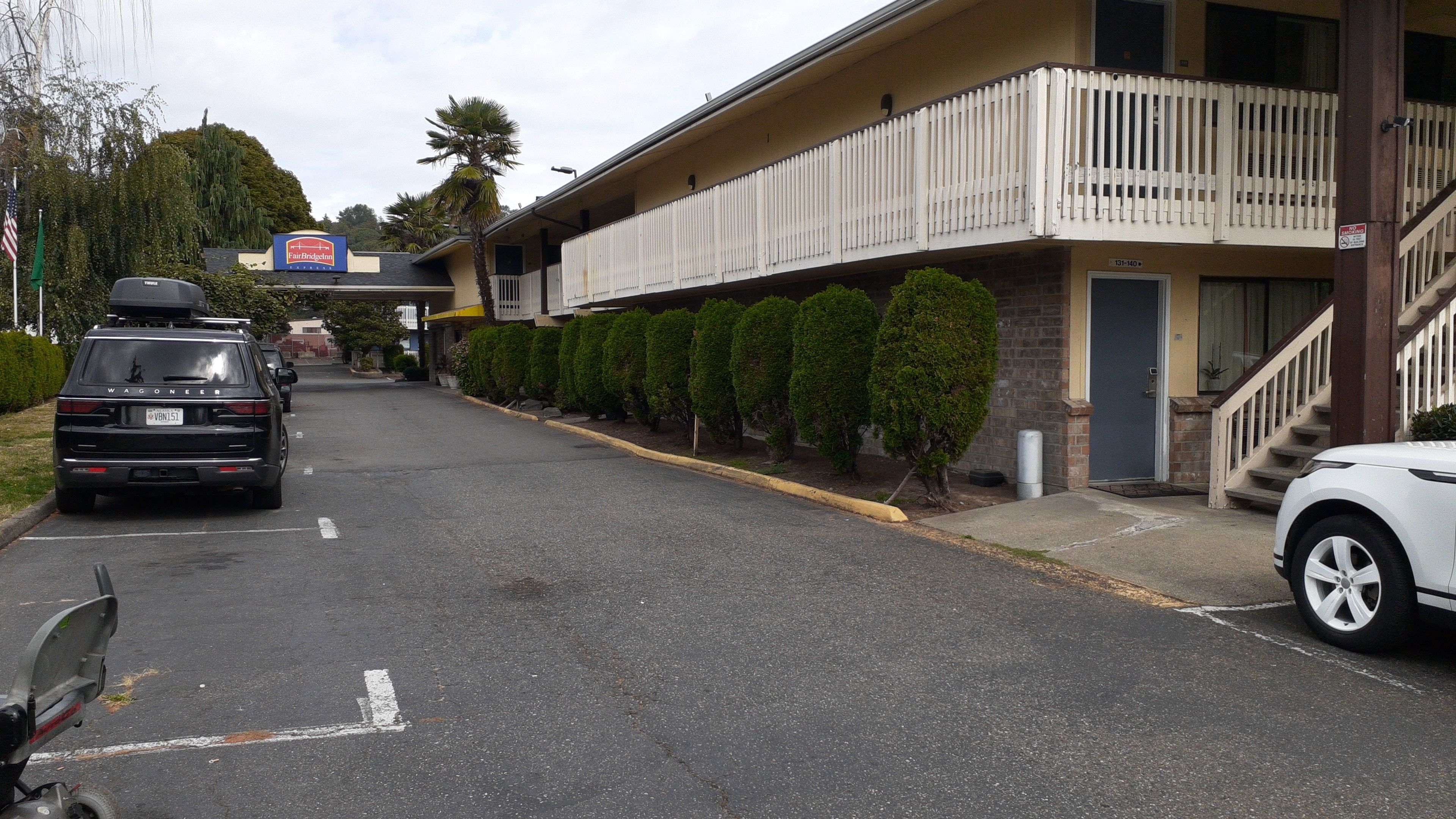 Un edificio con un cartel que dice 'Fairbridge Inn' y un estacionamiento con vehículos.