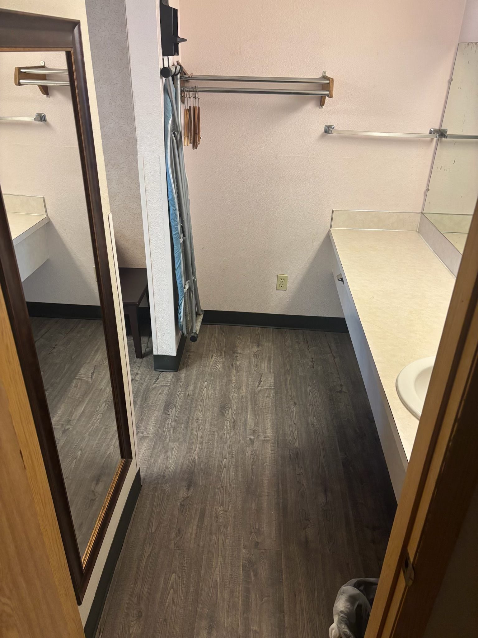 A bathroom with a wooden floor, a towel rack, a mirror, and a toilet.