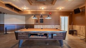 A pool table in a room with wooden paneling and pendant lighting. - Hotel Viewmont Residency Ltd. (Logan Lake)