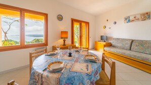 Un coin repas avec une table dressée pour quatre personnes, un canapé et un téléviseur posé sur un meuble.